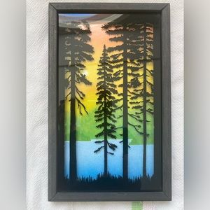 Silhouette painting on glass of pine trees at dusk.